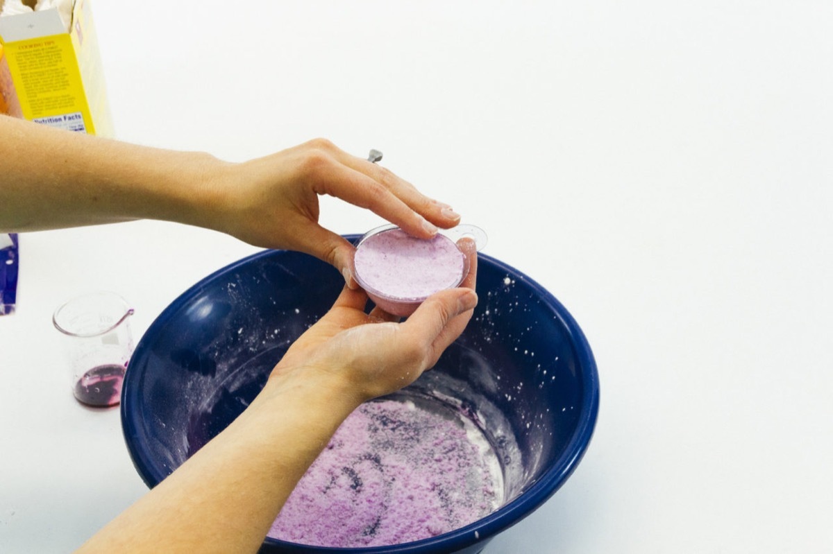 white hands making purple bath bomb