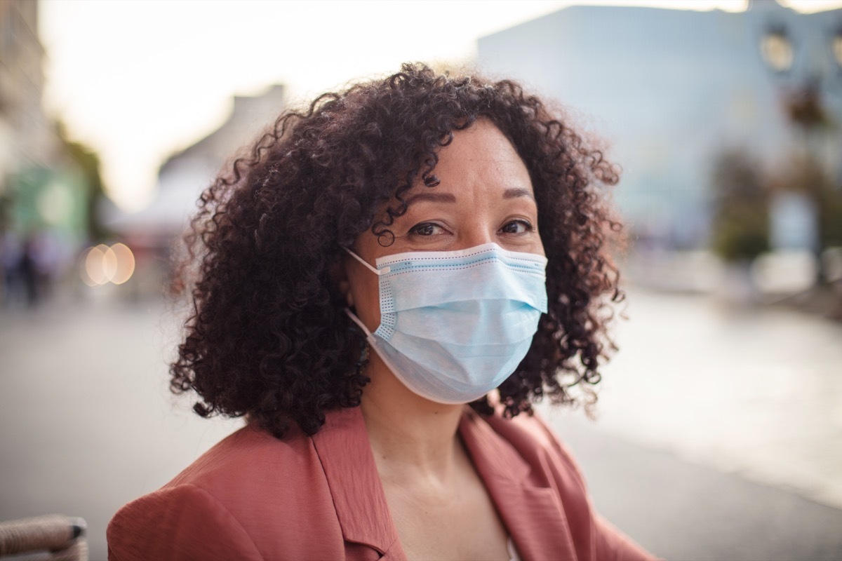 Woman with protective face mask sitting in café.