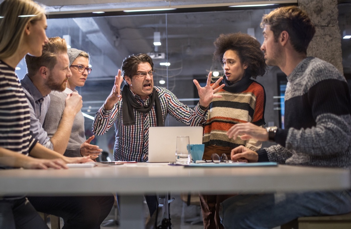 angry white boss shouting at his employees in an office