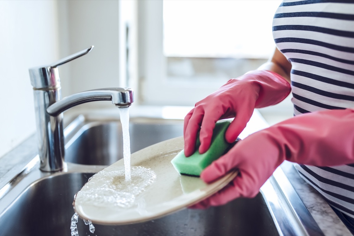 Woman washing dish in sink