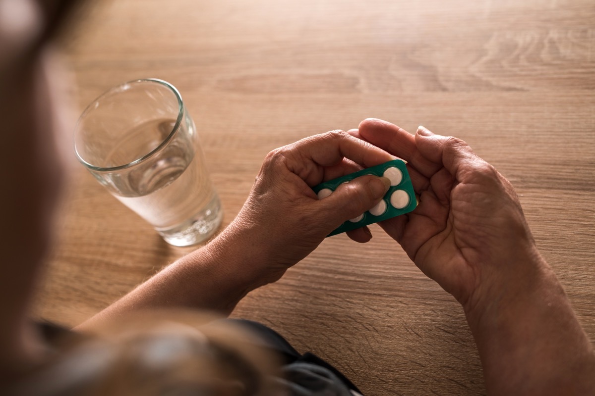 Close up of elderly woman taking a medicine out of blister pack.