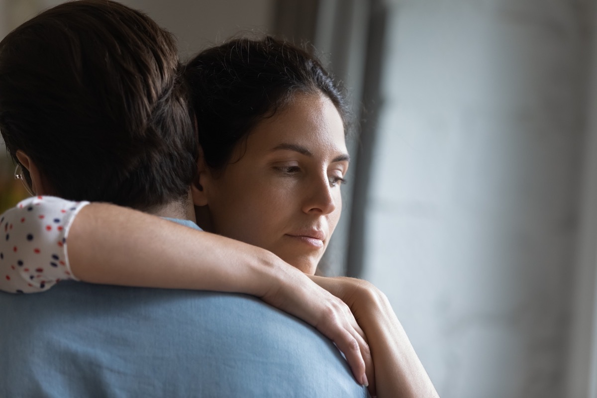 couple hugging while the woman looks sad