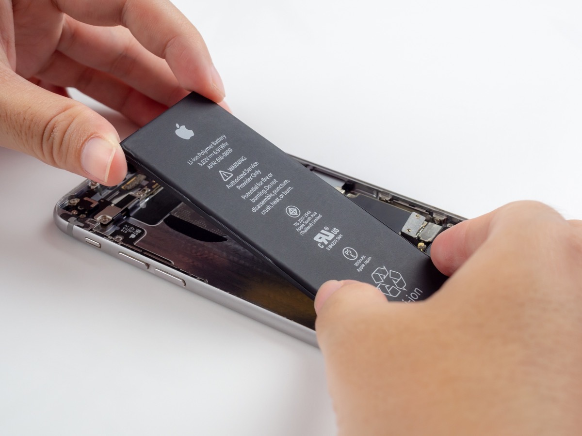 Chiang Rai, Thailand: September 13, 2018 - Close-up image of Technician hands tried to remove, take of, change or replace Apple iPhone 6 battery degenerate or damage.