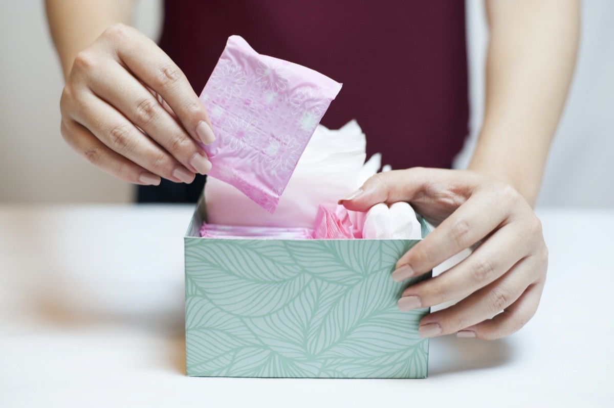 Woman picking sanitary pad out of green box