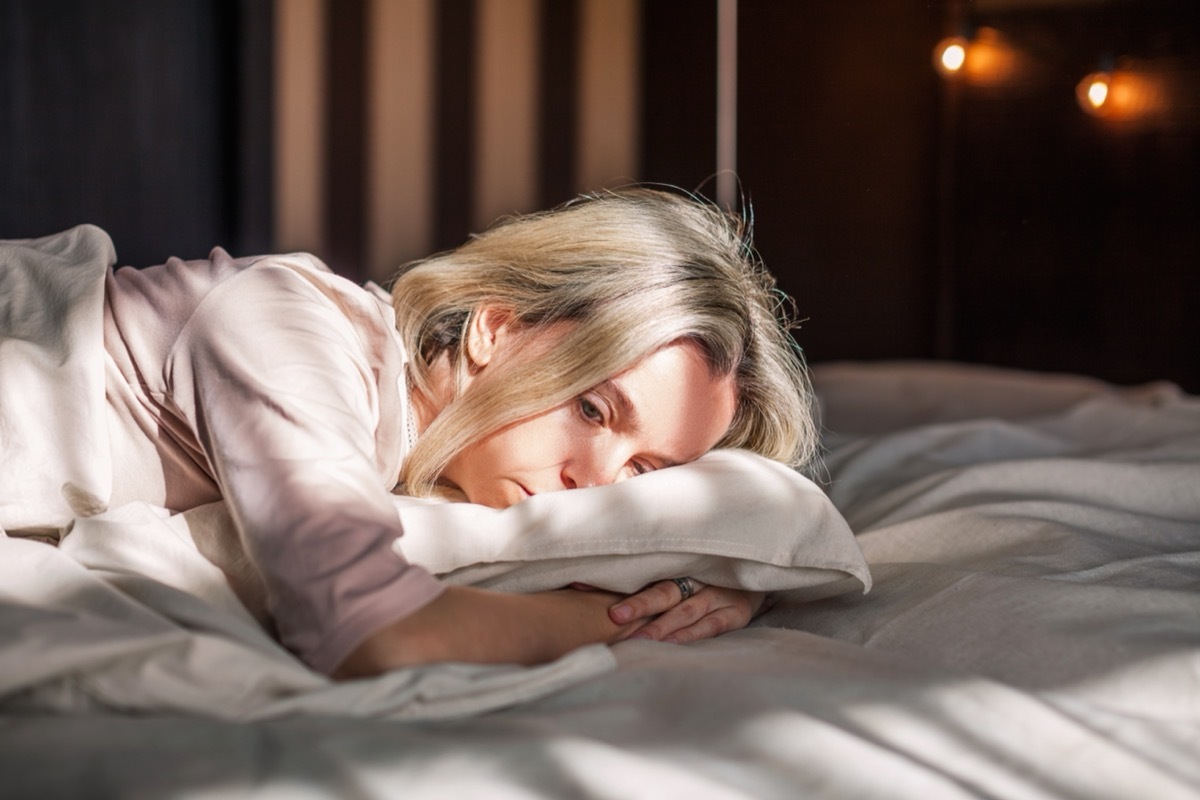 Tired middle aged woman lying in bed feeling depression