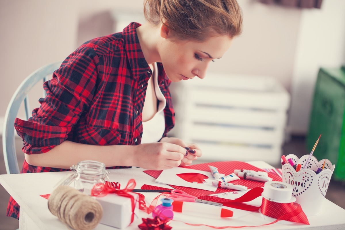 Woman creating gift at home with paper and gouache