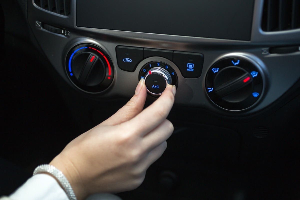 Woman turning on car air conditioning system