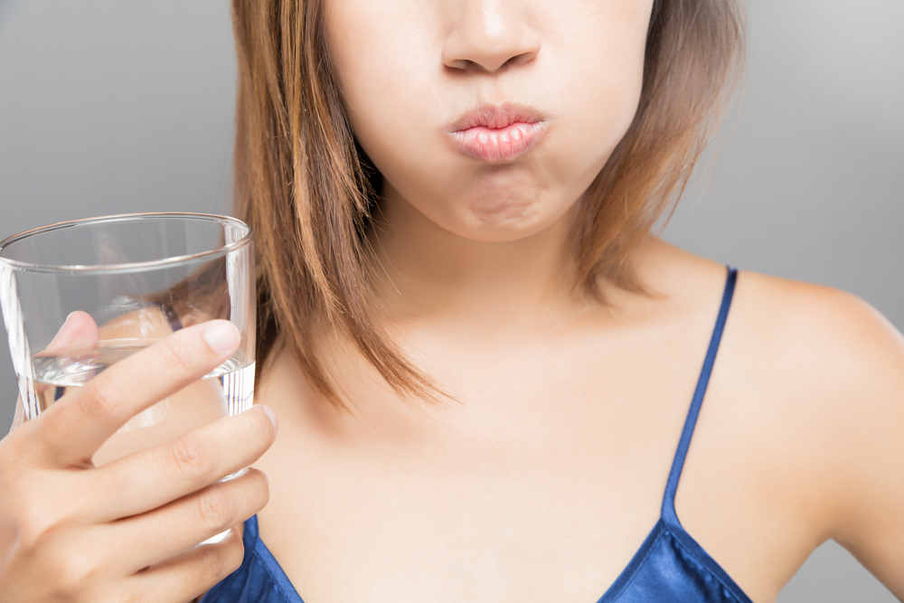 woman rinses with glass of water