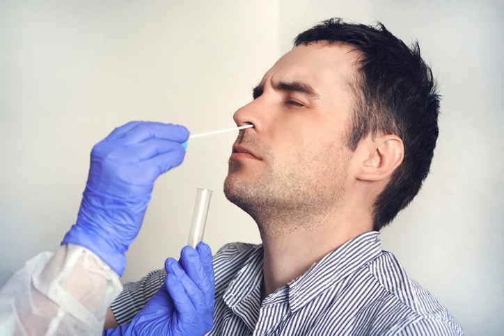 A Caucasian man has his nose swabbed for a coronavirus test