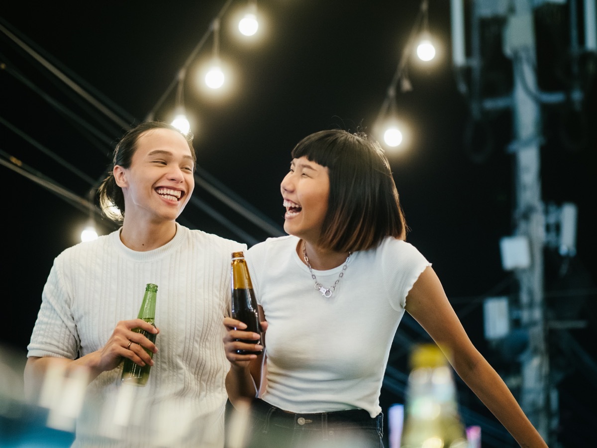 women toasting drinks with her boyfriend at a rooftop party.