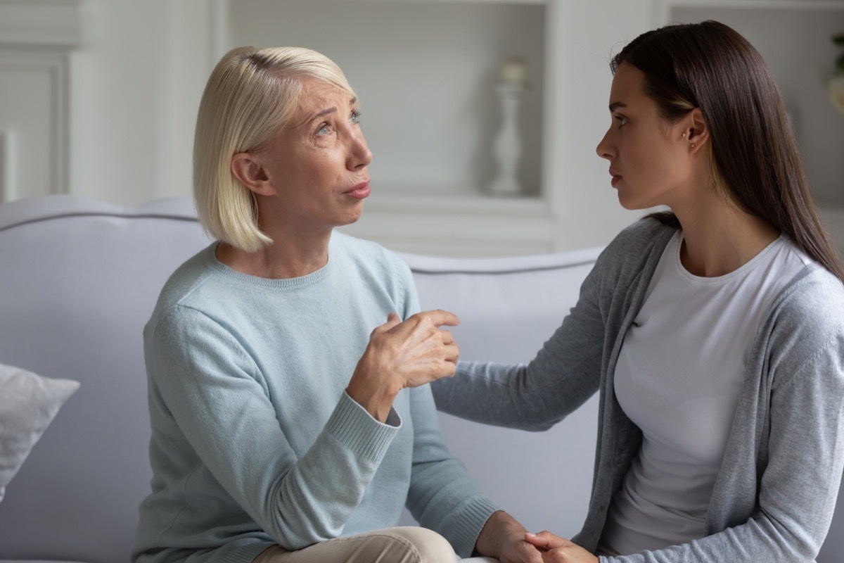 Young woman comforts upsets mature woman while sitting on couch