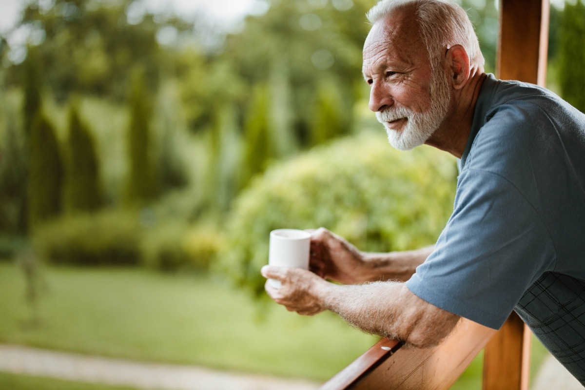 Senior man having his morning coffee on a balcony and day dreaming. Copy space.