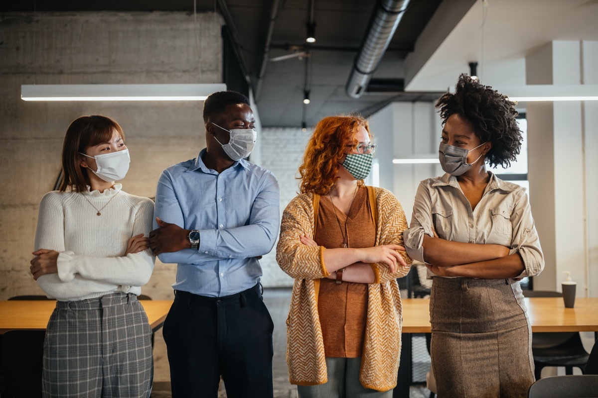 Team of colleagues with masks for protection from corona virus standing in the office