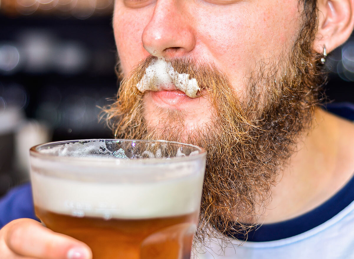 beer foam stuck in mans facial hair on upper lip