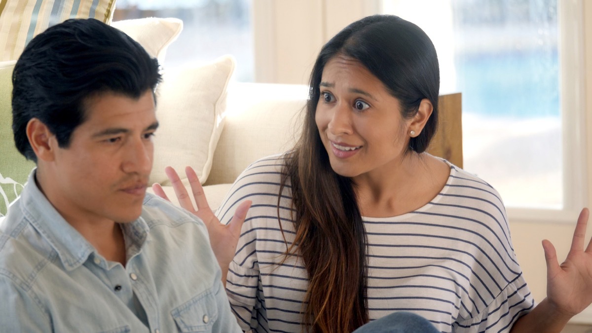 A woman raises up her hands in frustration with their argument, while her brother looks away annoyed.