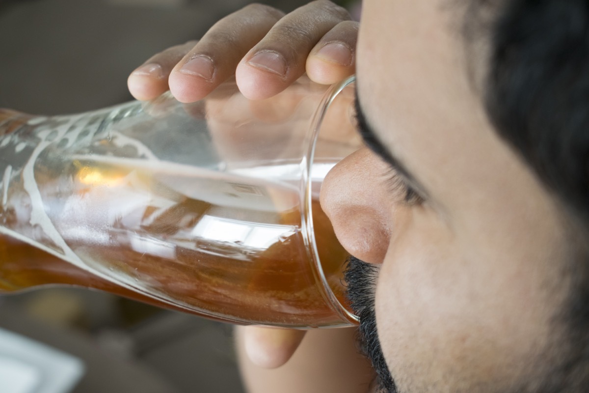 bearded man drinking a glass of light beer.