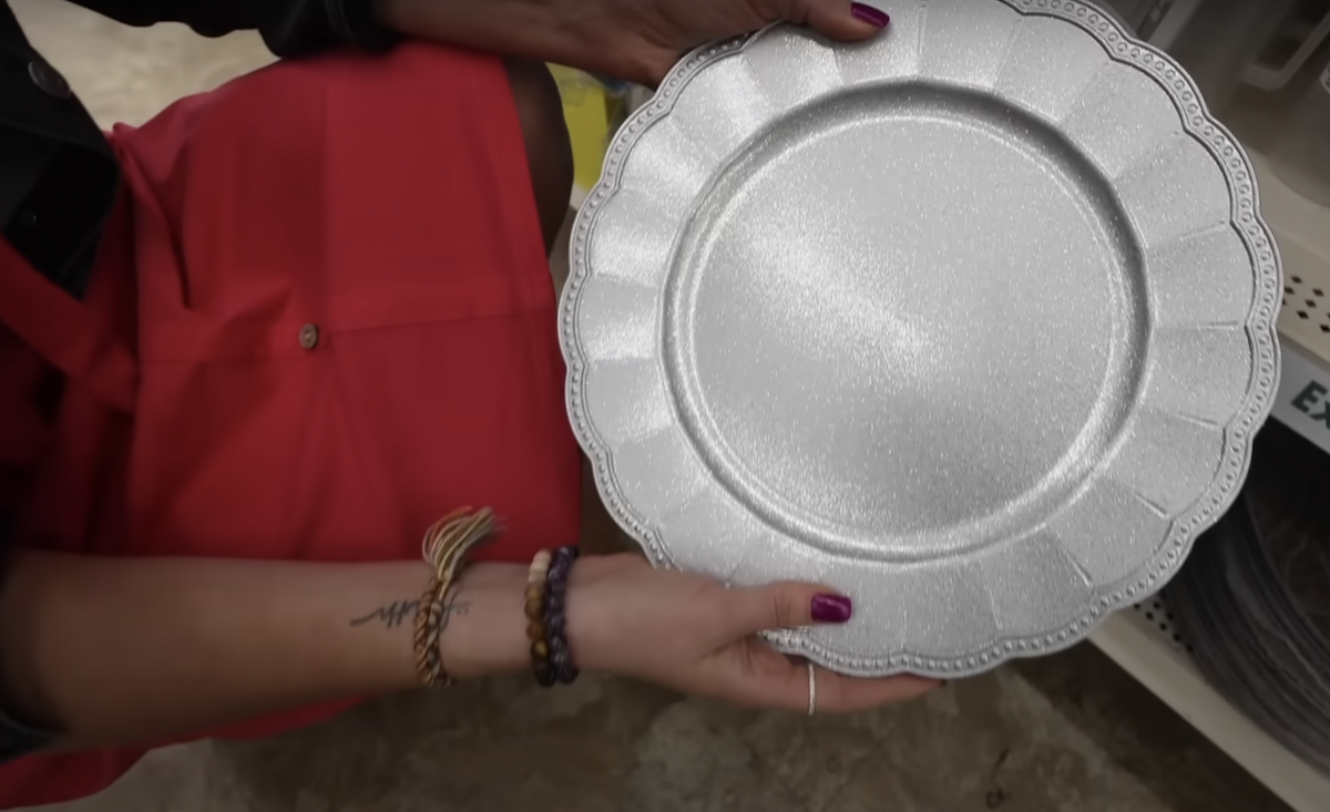 Still from a video of a shopper holding up a metallic charger plate from Dollar Tree