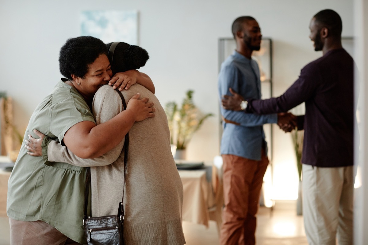 family welcoming guests at dinner party at home and embracing