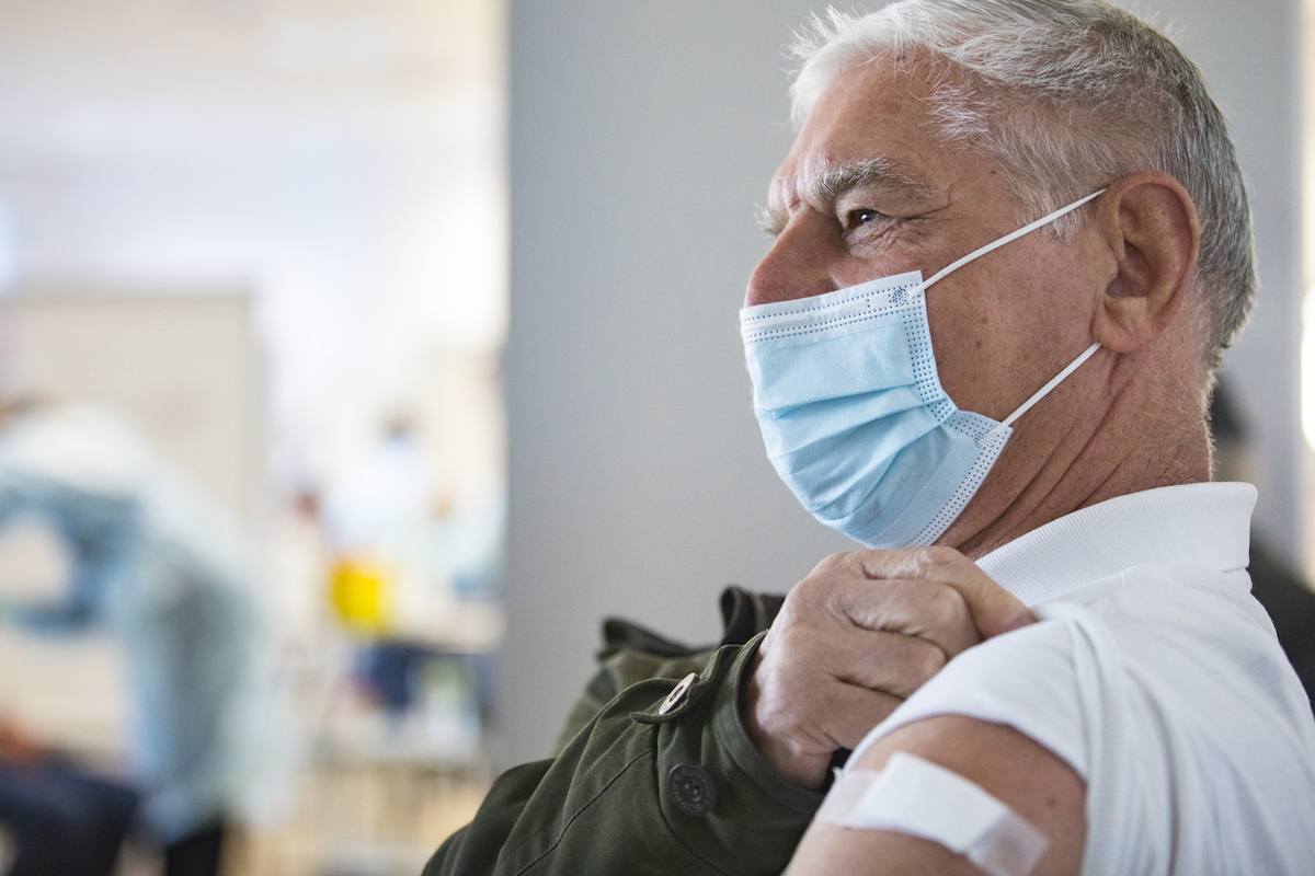 Senior Adult Man Sitting and Waiting in Field Hospital after Receiving COVID-19 Vaccine.