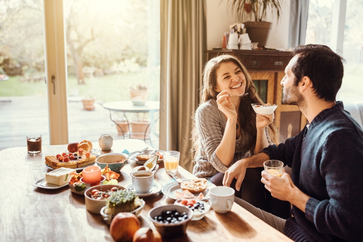 young couple sitting on a table and having breakfast together