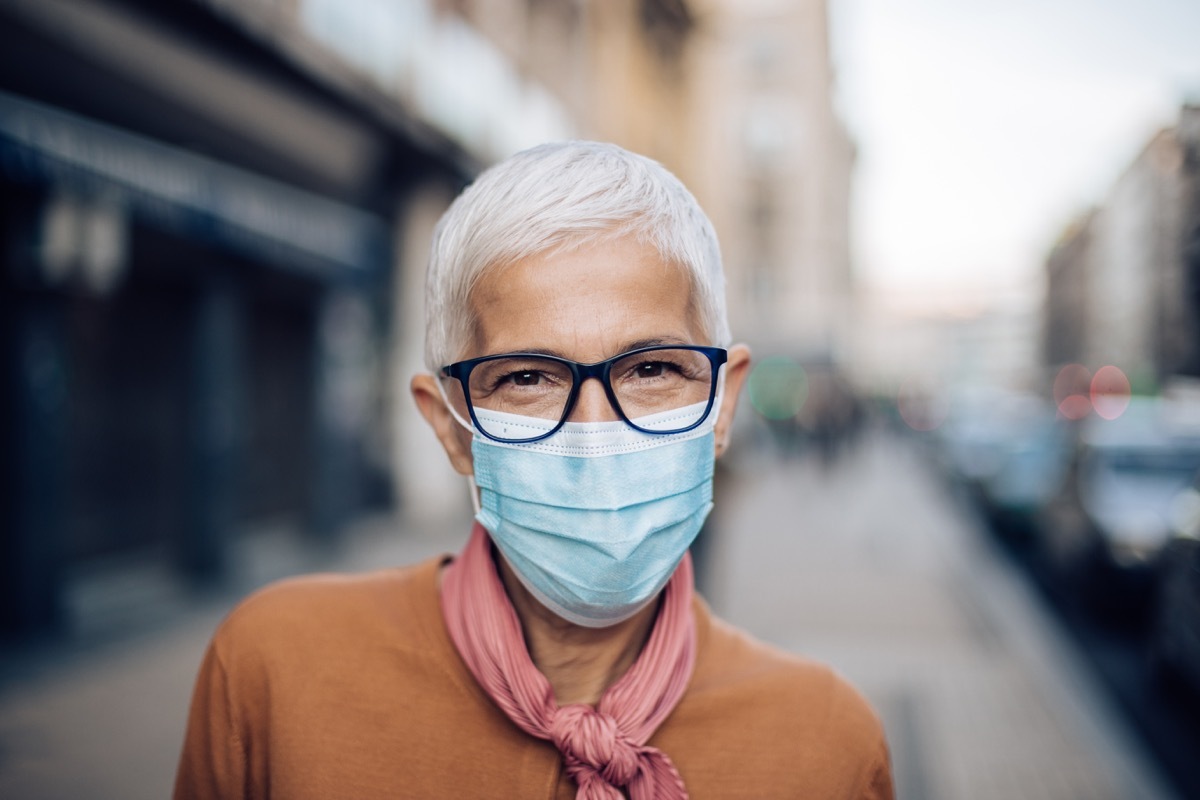 Portrait of an elderly woman in the city, wearing a protective face mask and the eyeglasses