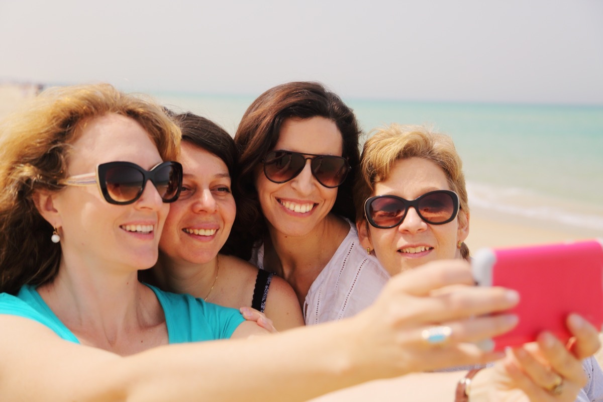 Older women smiling on the beach while taking a selfie