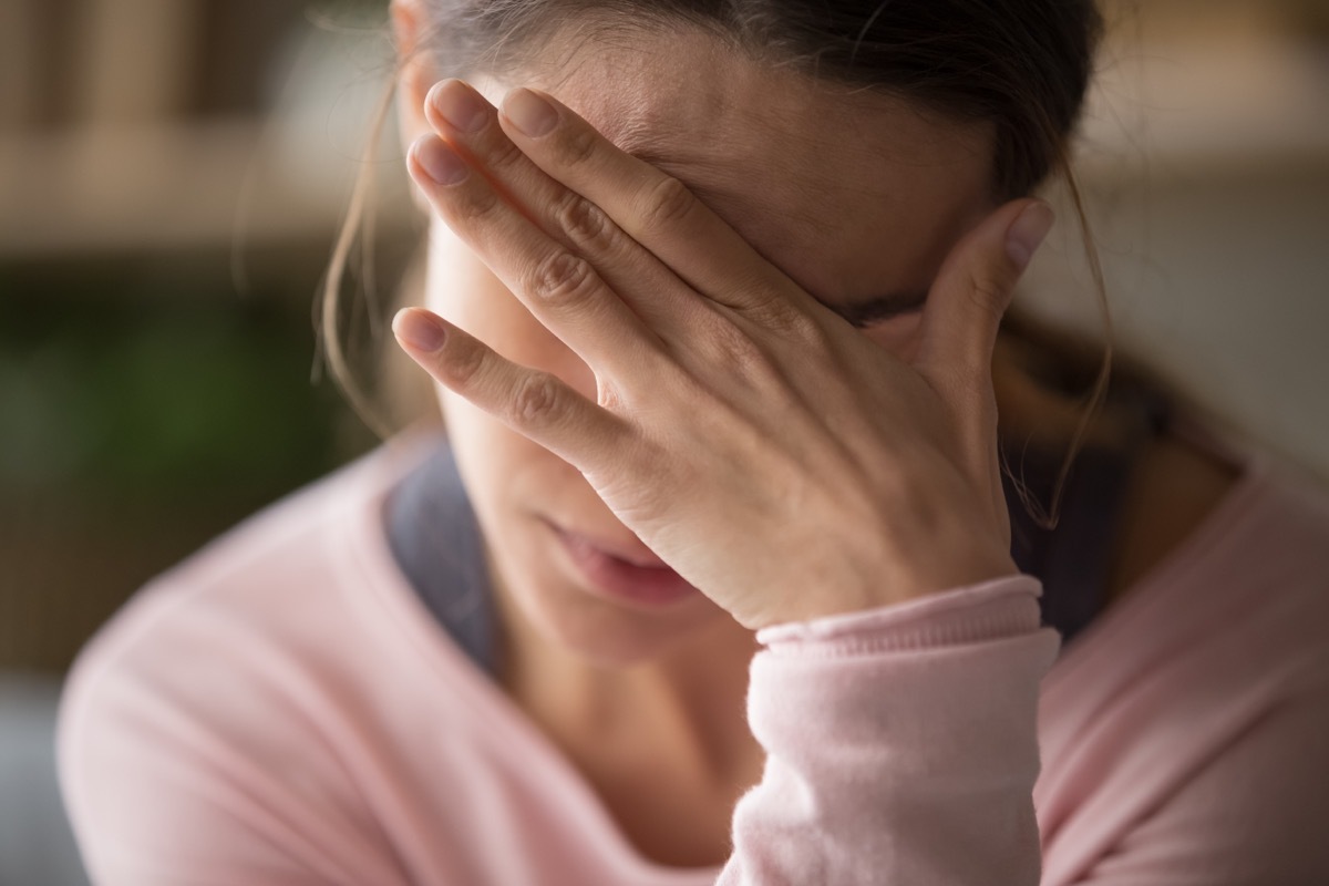 Anxious woman holding her hand up to her head.