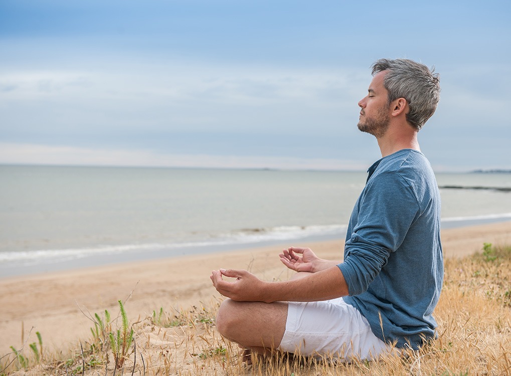 Man meditating on the beach