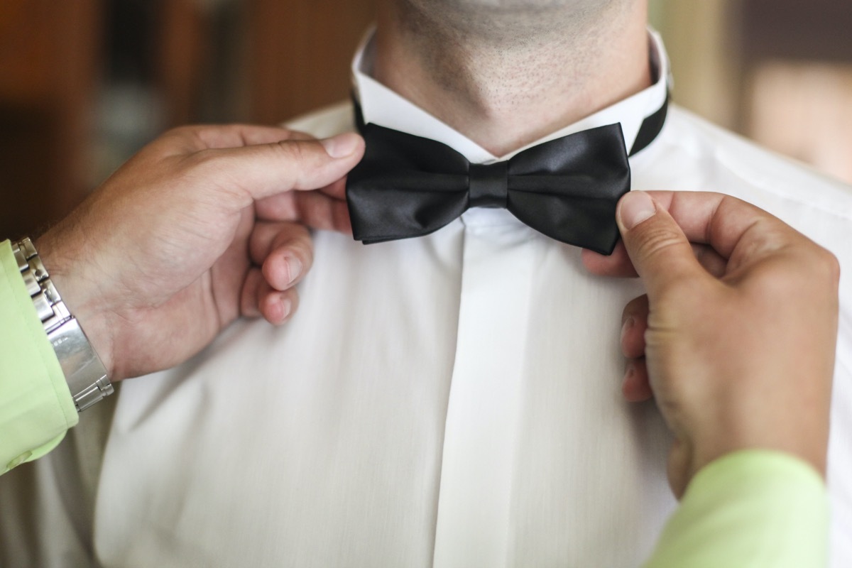 Unrecognizable man fixing bow tie on another man