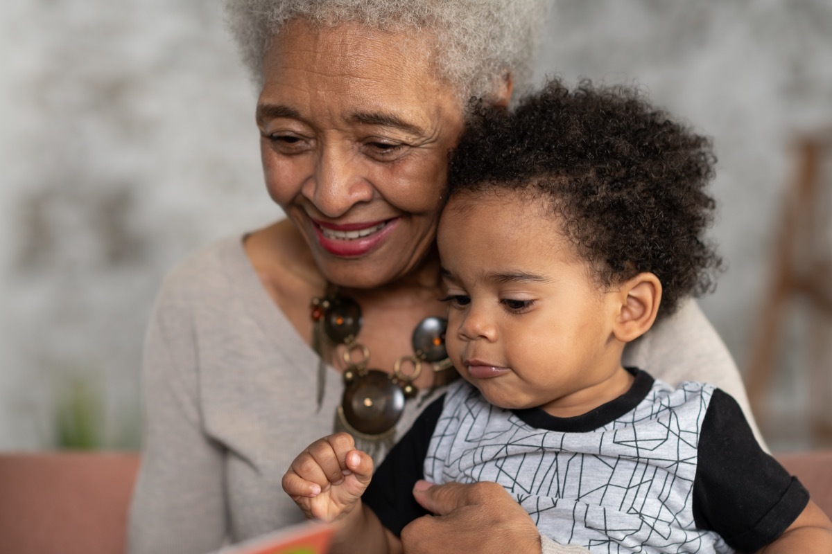 A grandmother is reading with her grandson. They are having a restful afternoon as they bond.