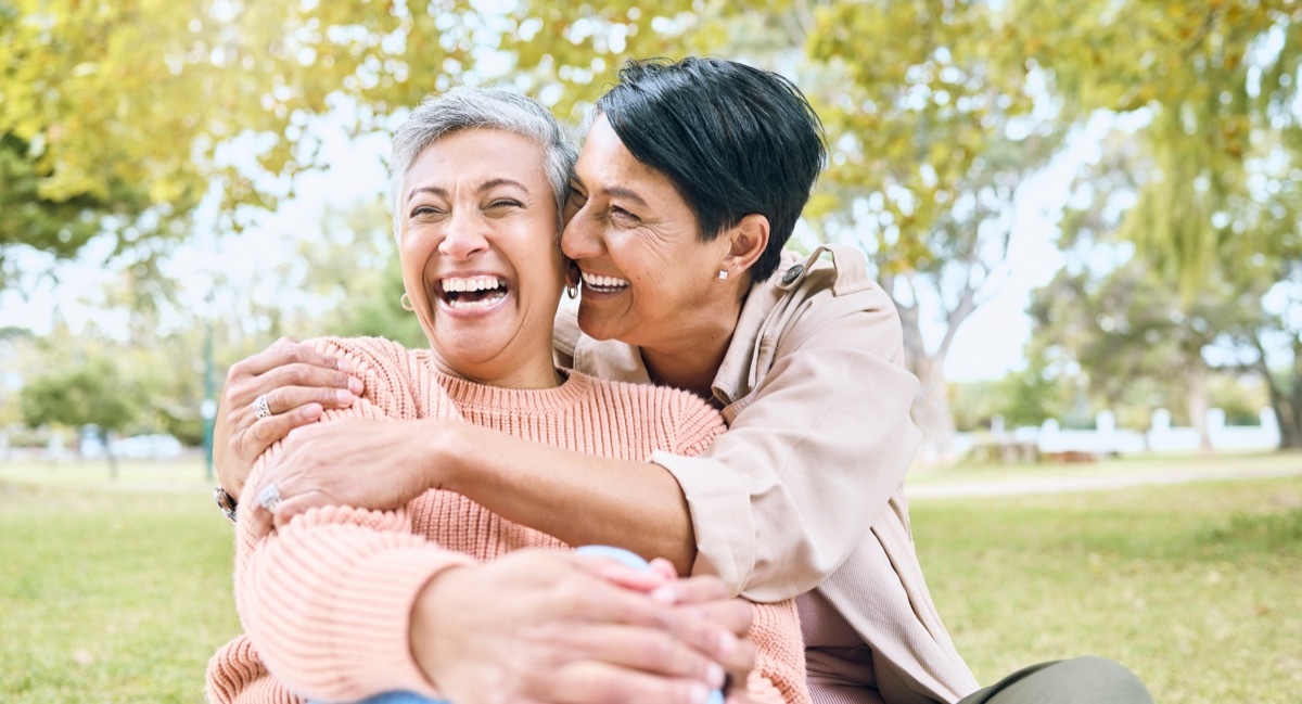 Woman hugging another woman from behind in the park