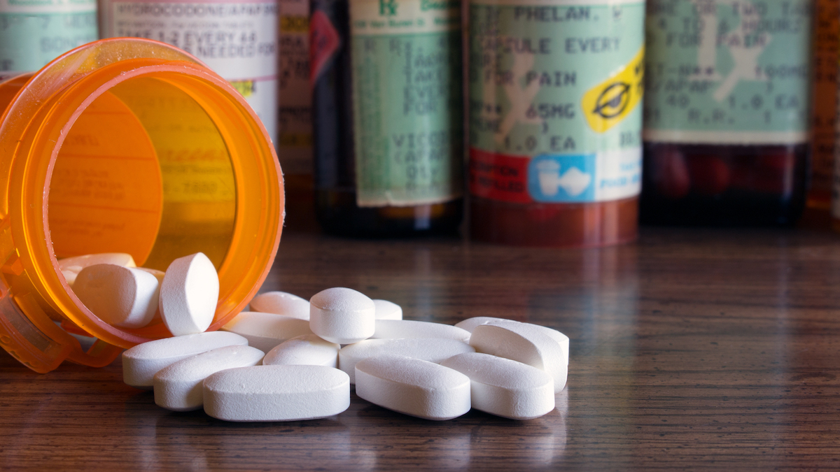 An orange prescription bottle with pills spilling out of it