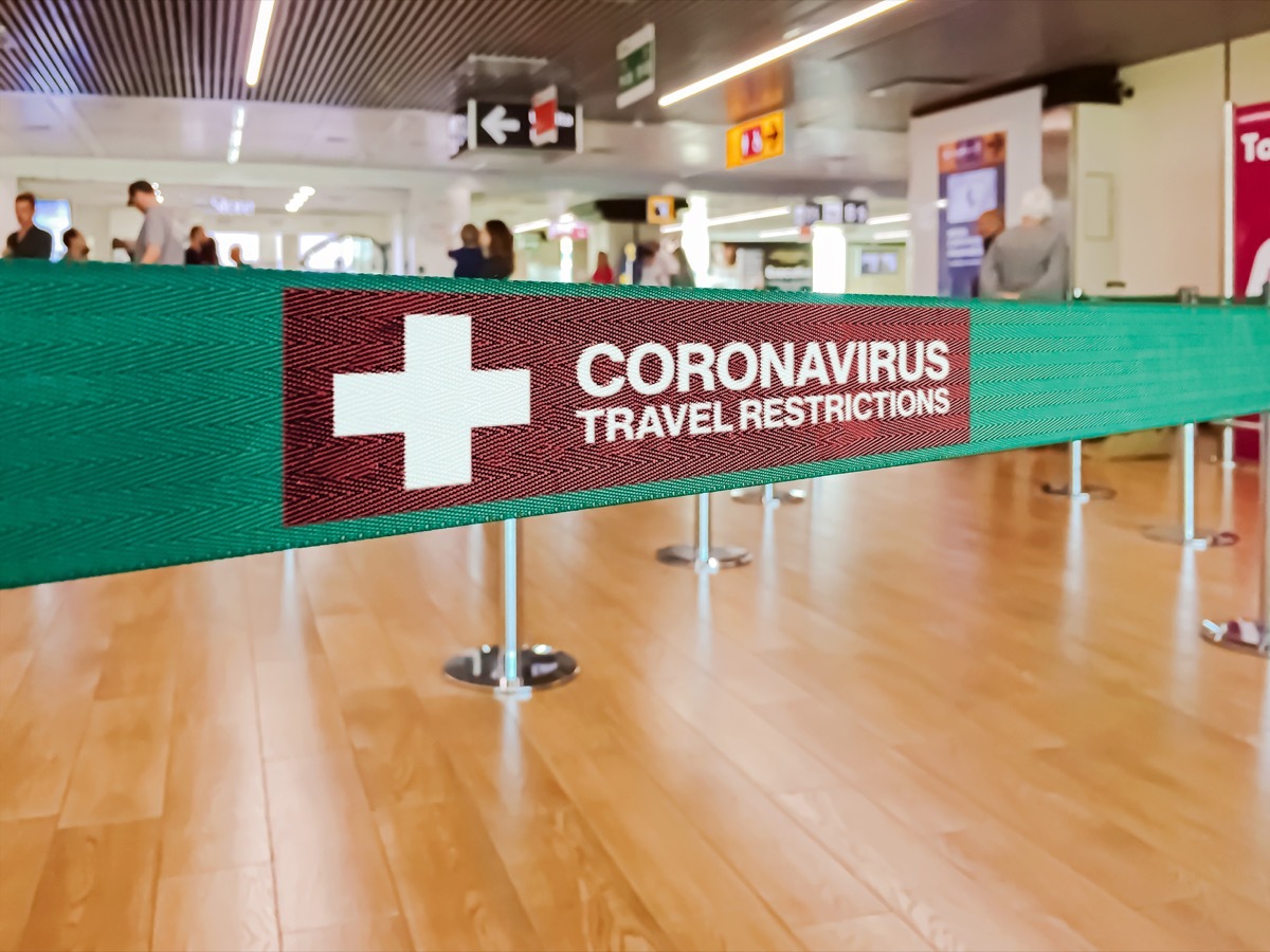 Green ribbon barrier inside an airport with the warning of travel restrictions due to the spread of the dangerous Coronavirus