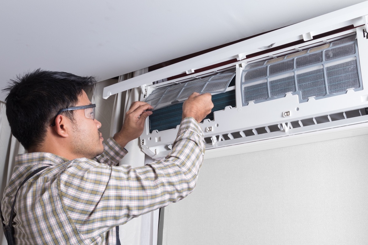 young asian man servicing a mini split hvac unit