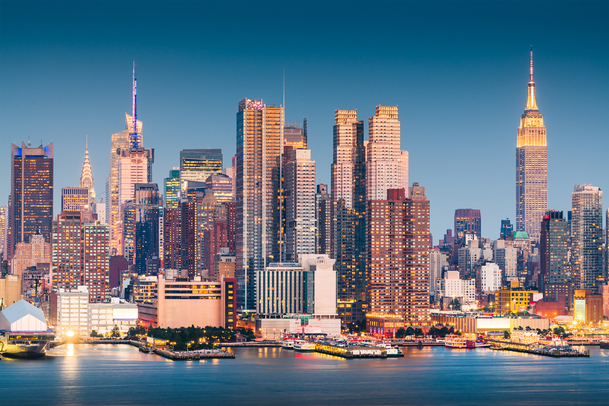 The skyline of New York City at sunset, with the Empire State Building and Midtown West in view