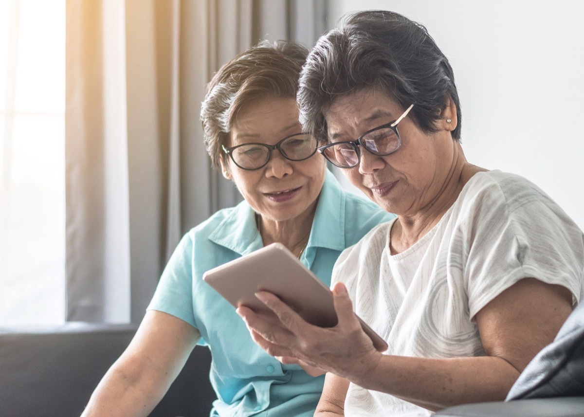 Asian senior adult women who look like twin sisters using mobile digital tablet