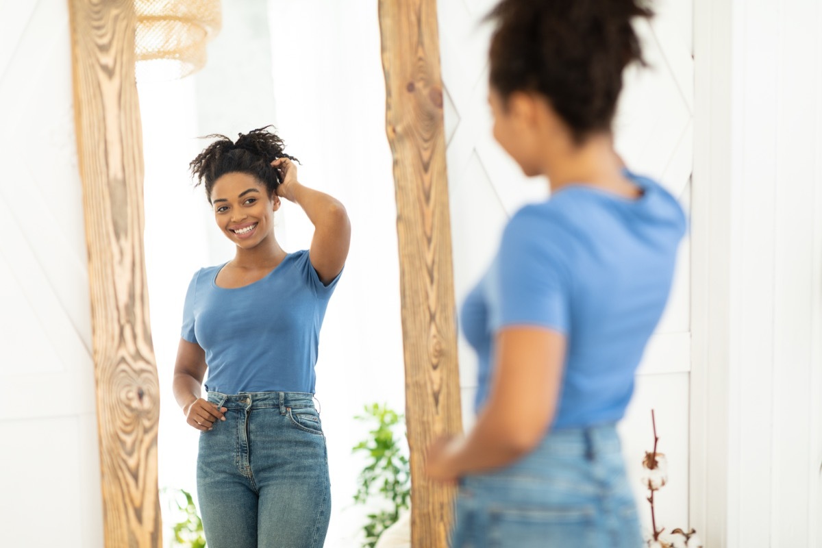 a confident woman looking into mirror