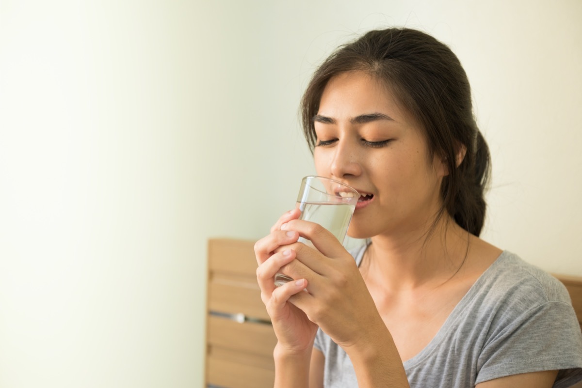 woman enjoy drinking water in the morning after wake up on the bed