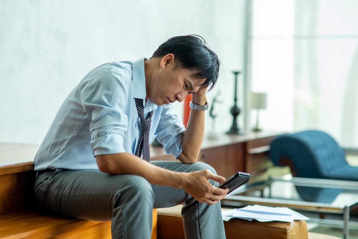 Depressed man employee have a bad new from smartphone and think of problem.