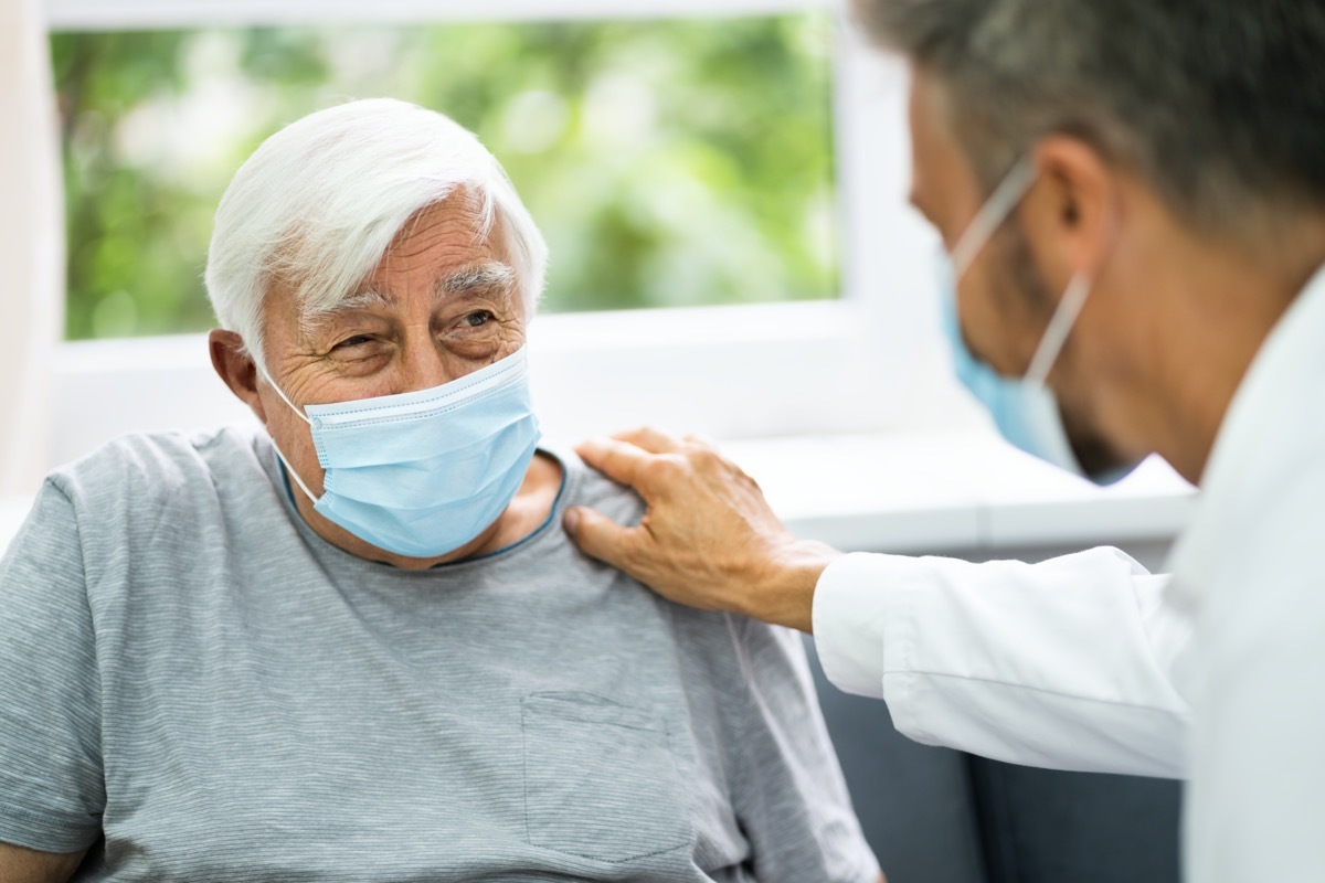 doctor talking to elderly patient wearing mask