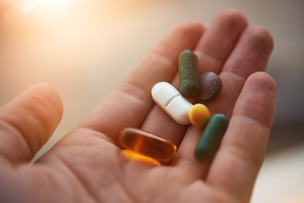 Assorted vitamin supplement pills resting in the palm of a hand