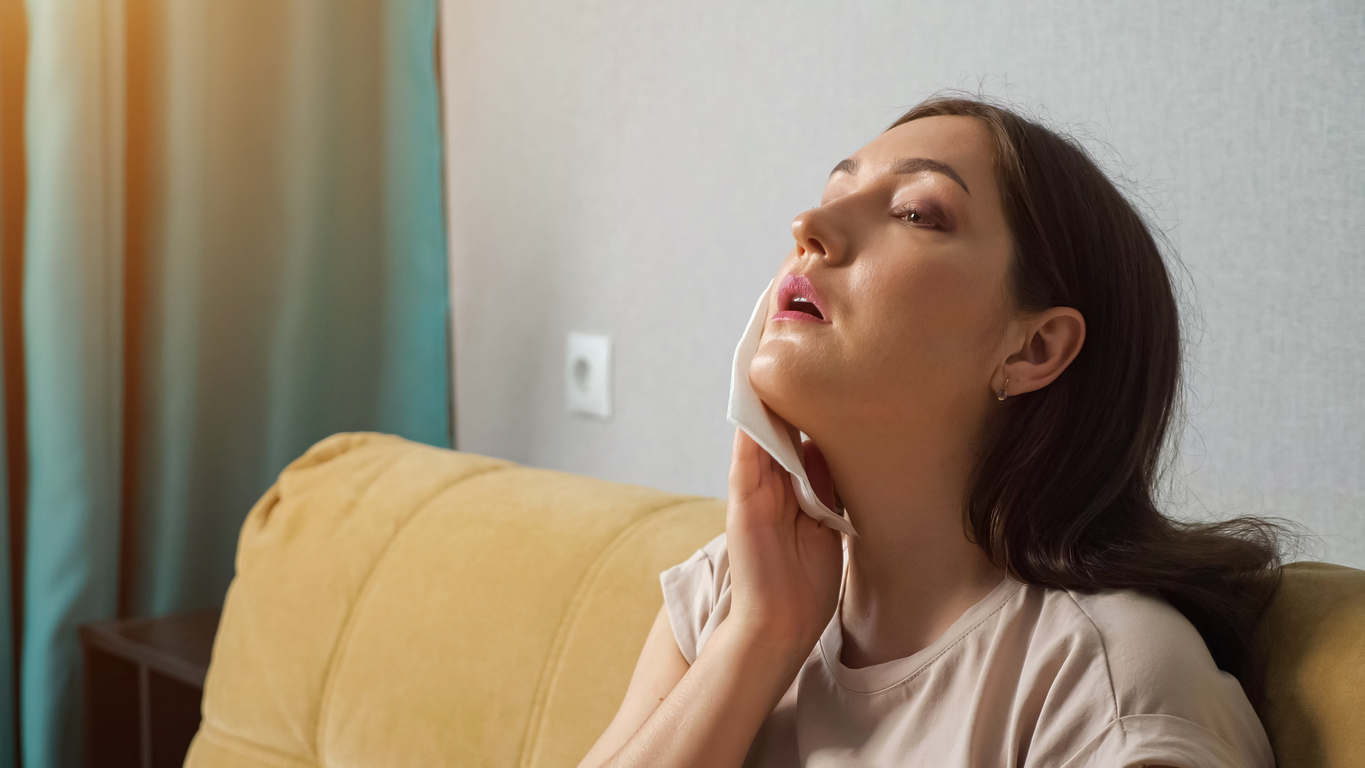 Woman wiping at perspiration on her face.