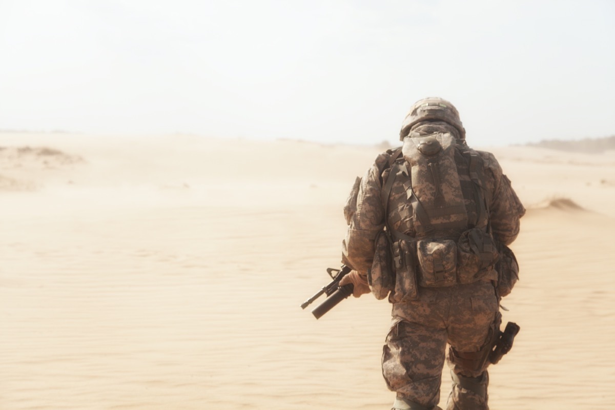 military man from behind heading into a desert