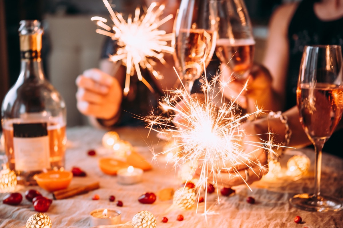 Friends celebrating Christmas or New Year eve party with Bengal lights and rose champagne.