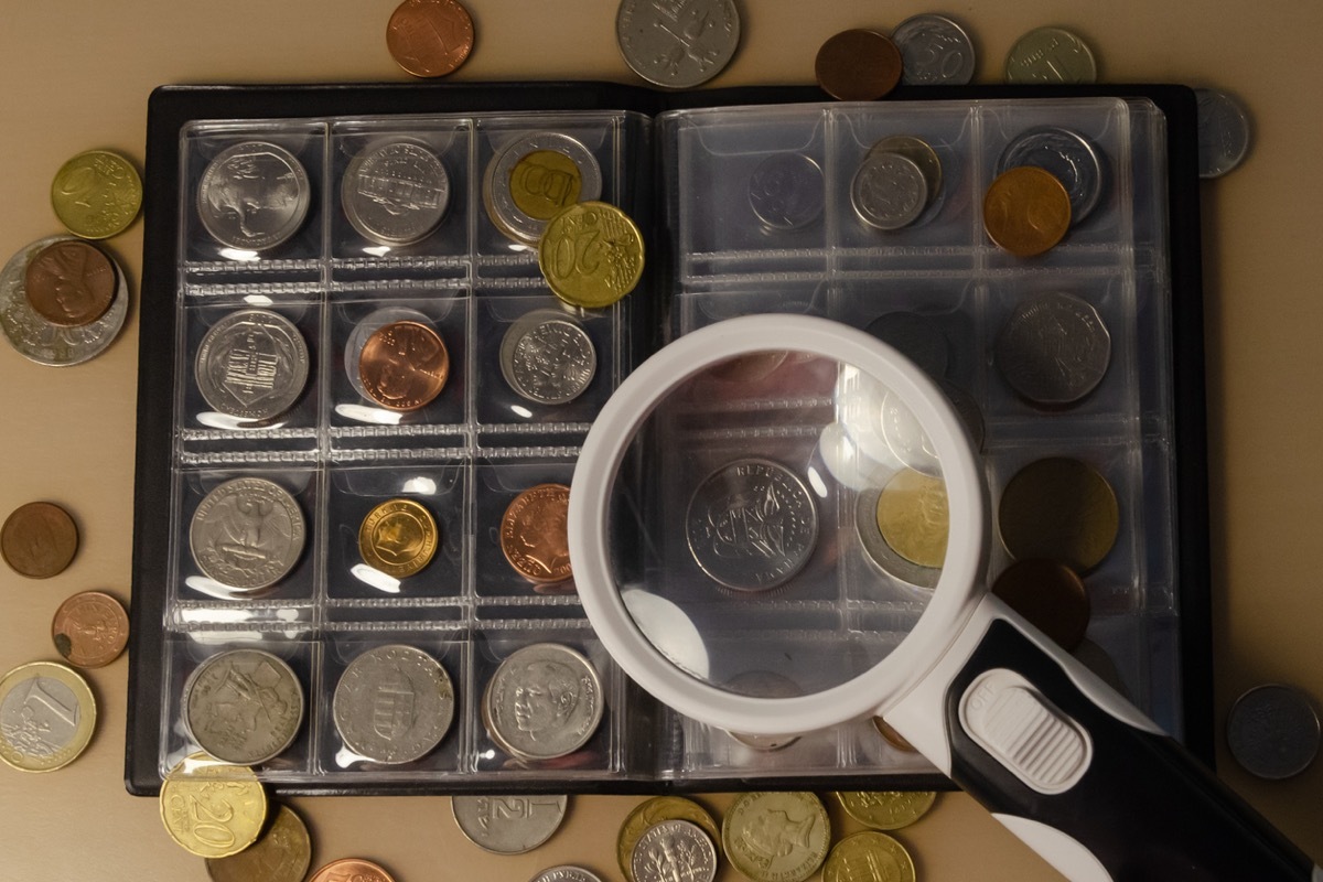 working with a collection of coins on the table magnifying glass close-up