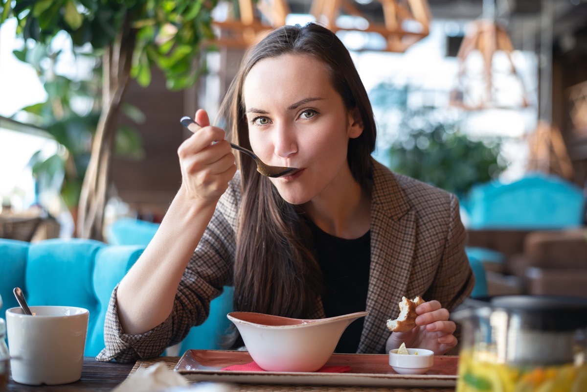 brunette woman eating soup in restaurant