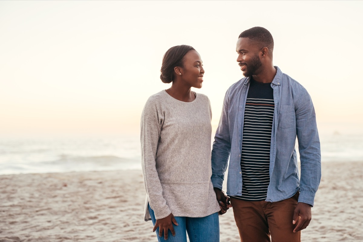 young black couple walking on beach