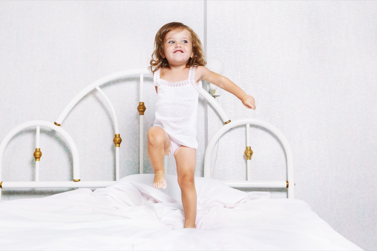 Toddler girl jumping on bed