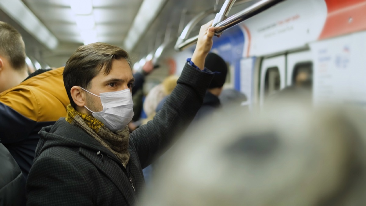 white man with face mask on crowded subway train