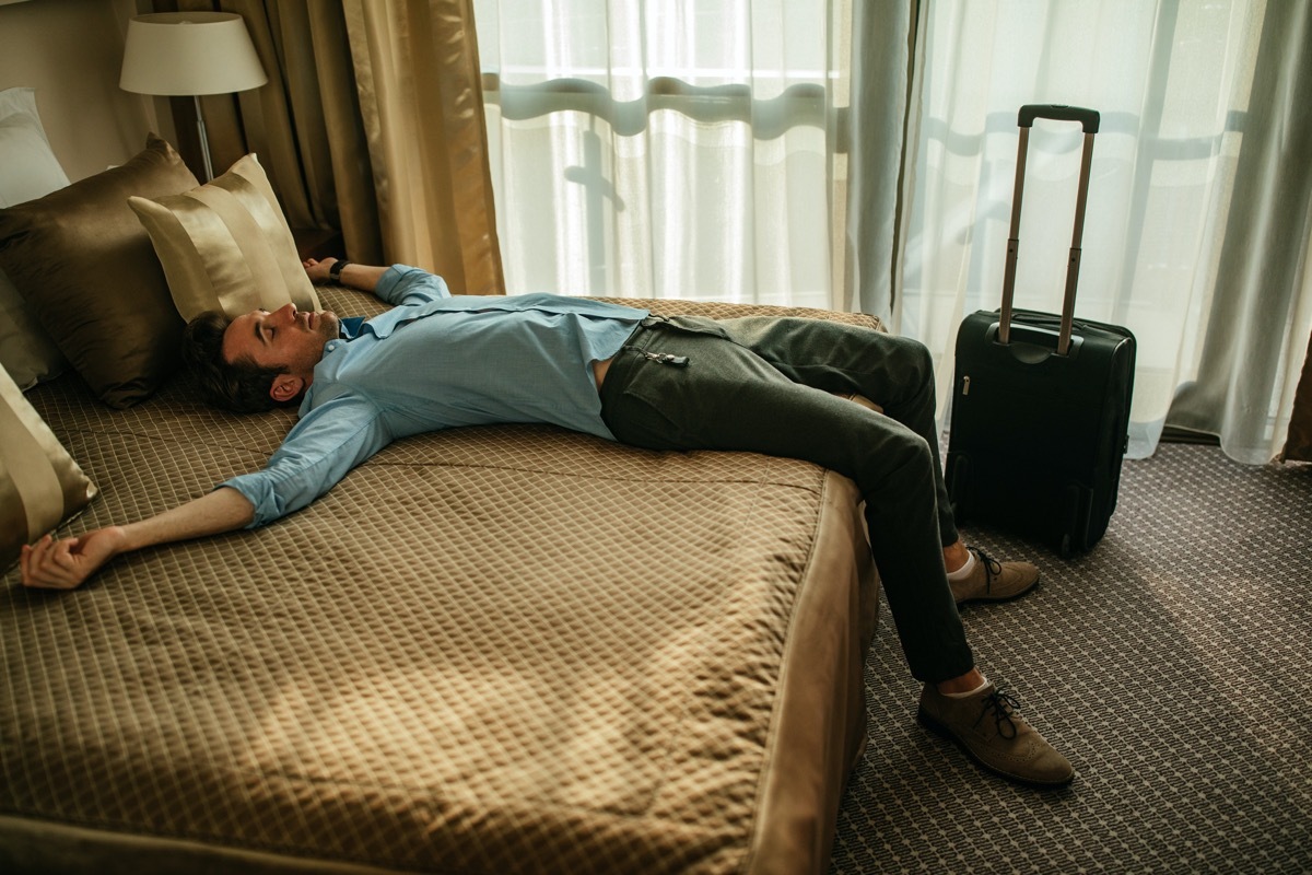 Tired man lying on the bed in a hotel room